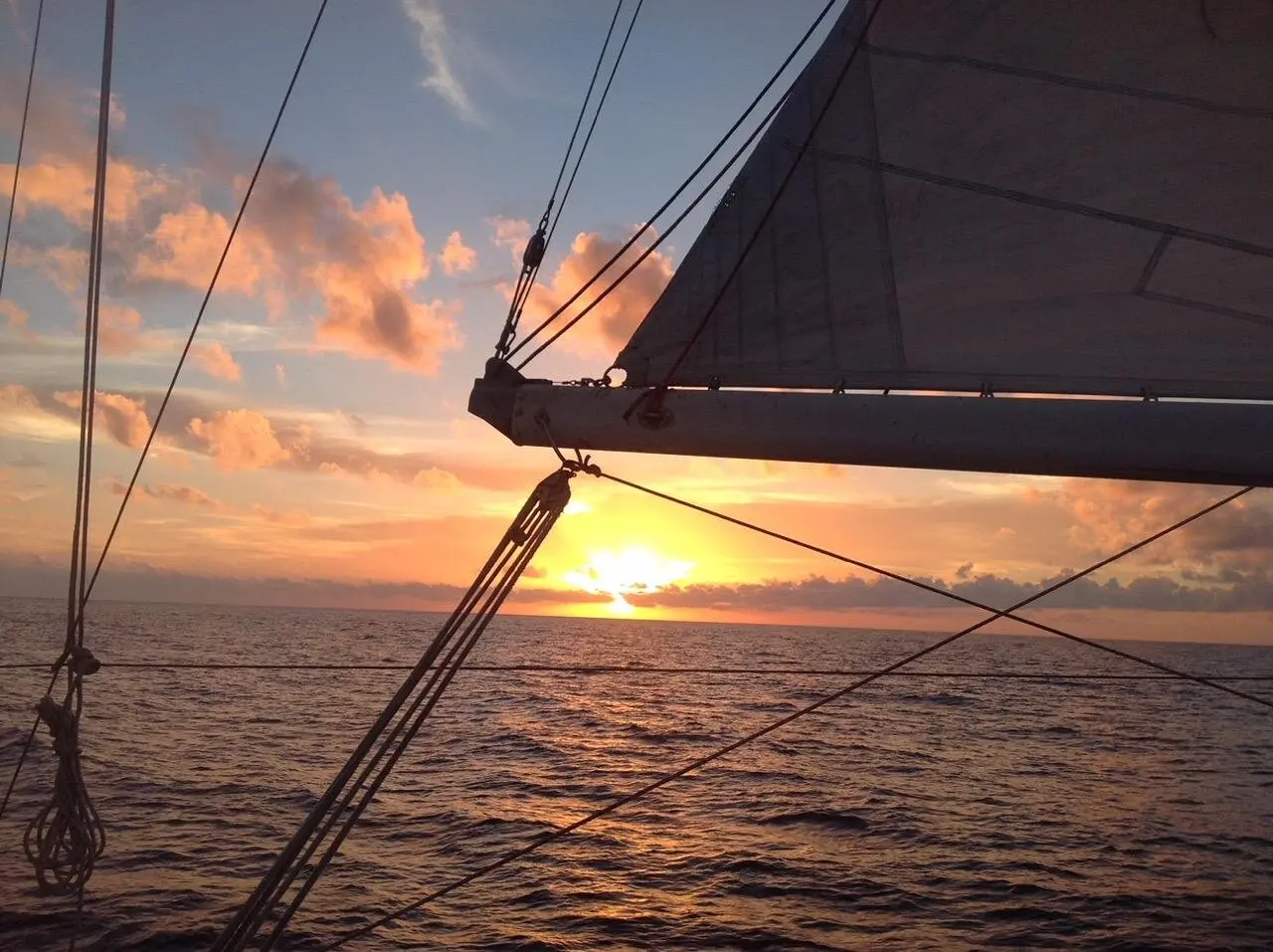 Sunset view over the water with the boat's boom in the foreground