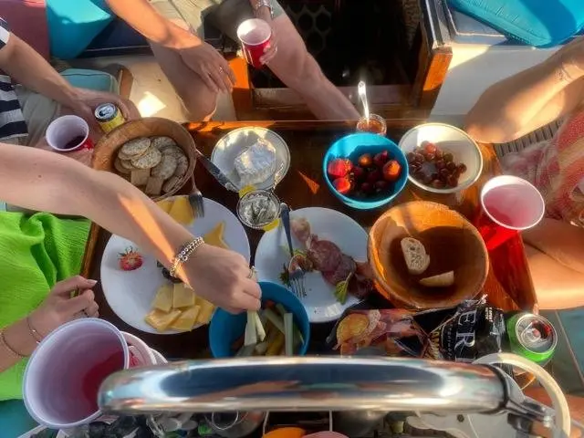 A picnic table of snacks including cheese, crackers, grapes and strawberries