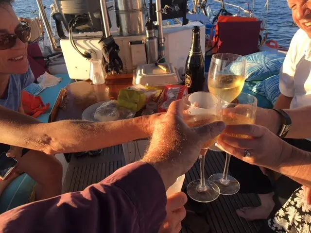 Guests on the boat celebrating with wine and champagne at sunset