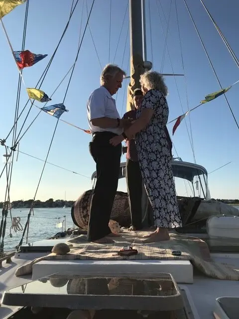 A couple holding hands on the boat's deck at sunset