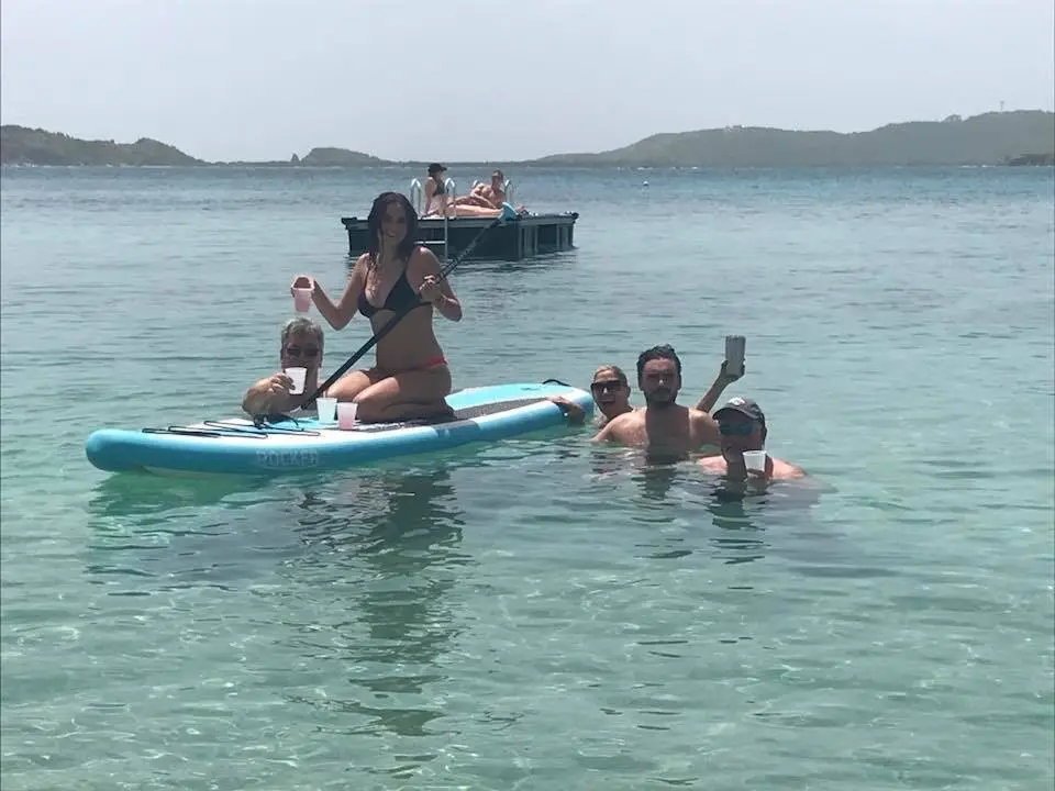 Guests enjoying a beach day, some in the water and some on a paddleboard