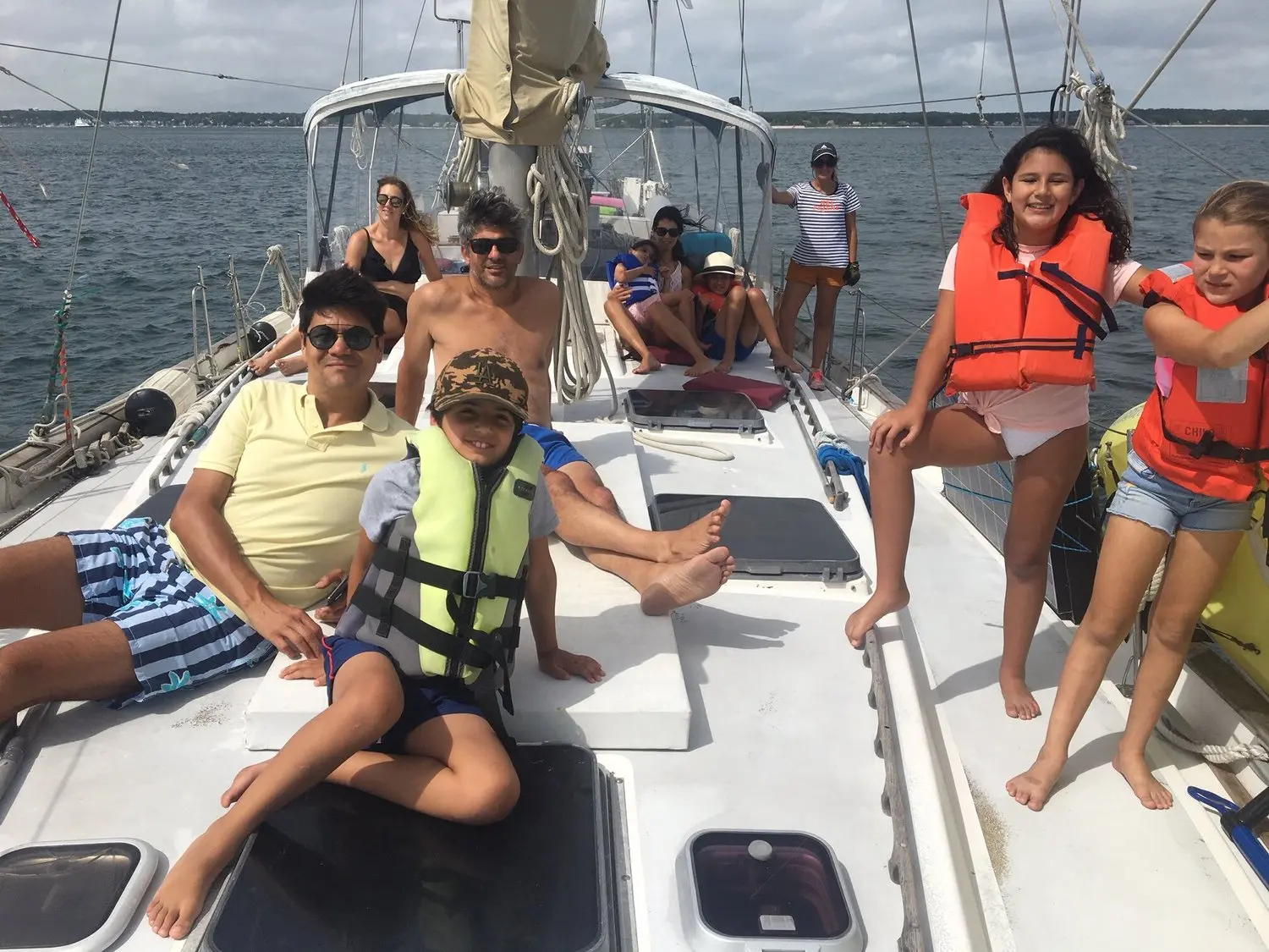 A group of nine guests, including children, on deck during an overcast day